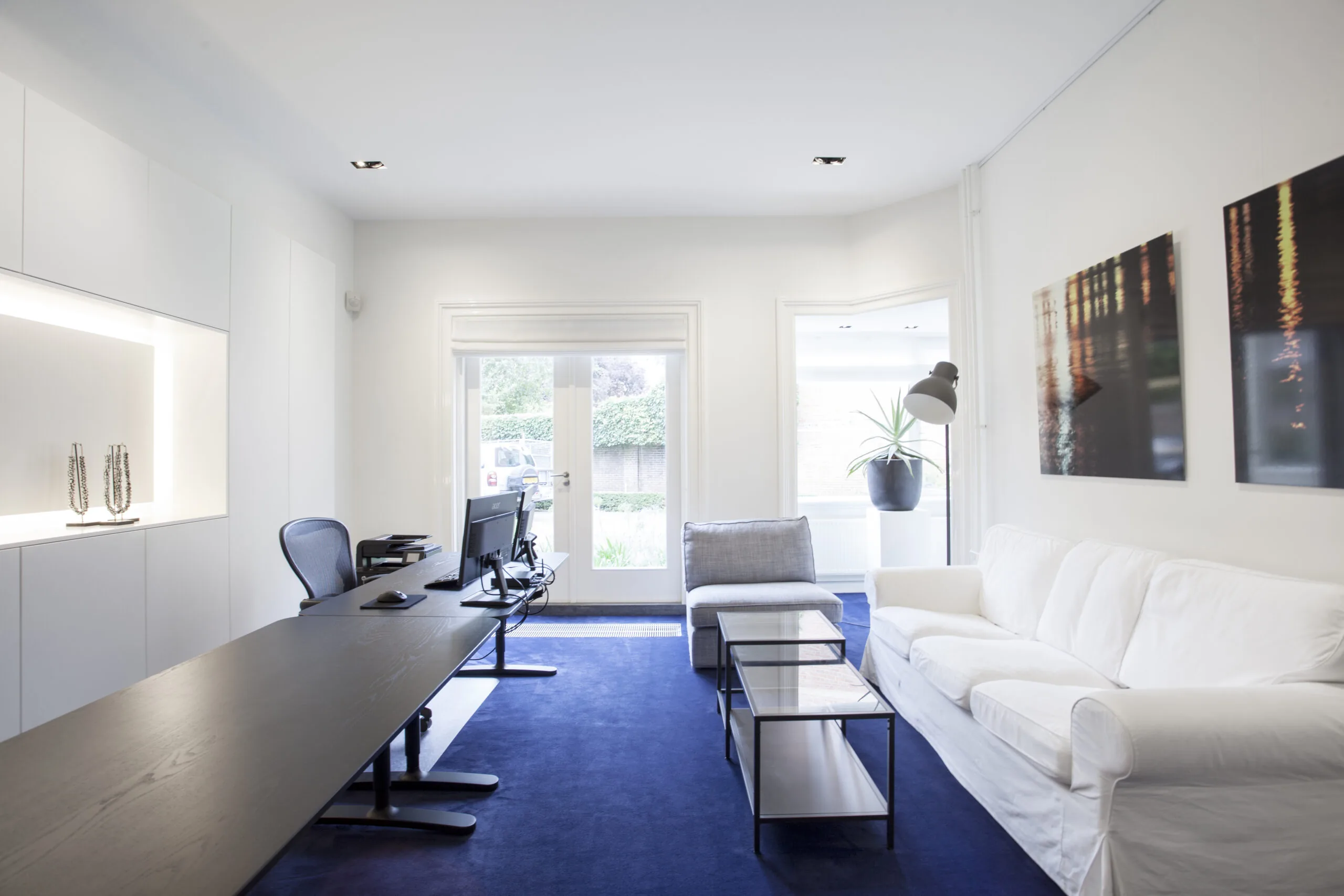 Moderne kantoorruimte op Sweelinckplein 1-9 met een strak interieur, blauwe vloerbedekking en veel natuurlijk licht.