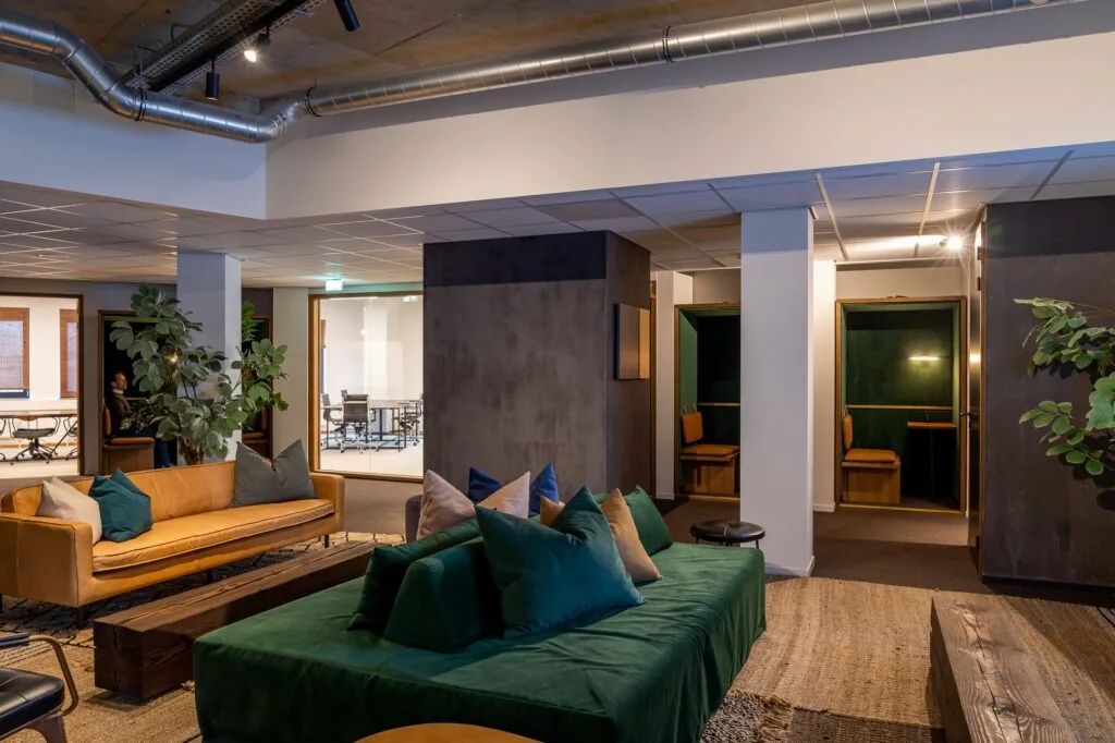 Modern ingerichte lounge- en werkruimte in kantoor Emmasingel 33 met comfortabele zitbanken en afgesloten werkplekken.