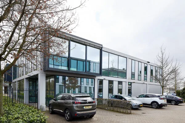Modern kantoorgebouw aan de Floridadreef 112 met grote ramen en parkeerplaatsen voor de deur.
