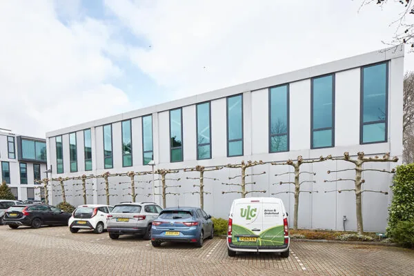 Moderne kantoorruimte aan de Floridadreef 112 met parkeerplaatsen en geparkeerde auto's op de voorgrond.