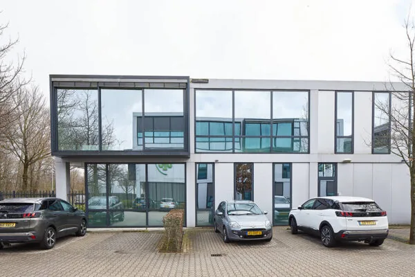 Modern kantoorgebouw aan de Floridadreef 112 met grote glazen ramen en geparkeerde auto's op de voorgrond.