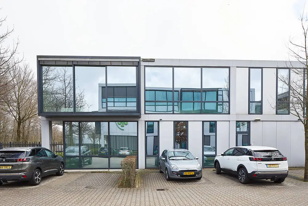 Modern kantoorgebouw aan de Floridadreef 112 met grote glazen ramen en geparkeerde auto's op de voorgrond.