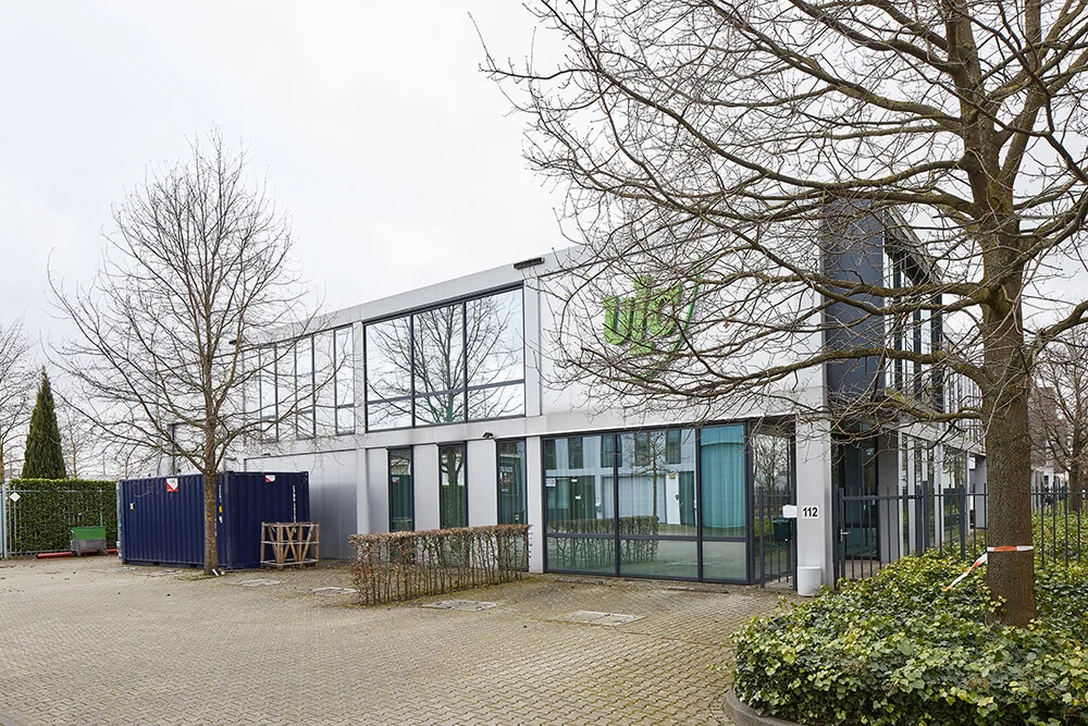 Modern kantoorgebouw aan de Floridadreef 112 met grote ramen en omringende bomen.