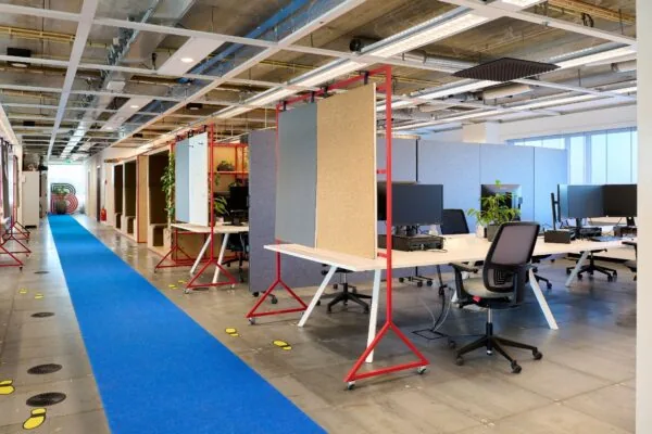 Moderne kantoorruimte aan de Johan Huizingalaan 400 met flexplekken, scheidingspanelen en een opvallende blauwe loper.