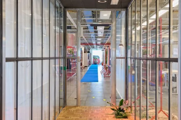 Moderne kantoorruimte aan de Johan Huizingalaan 400 met glazen wanden, kleurrijk interieur en blauwe loper in de gang.