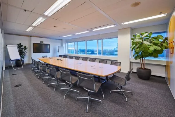 Vergaderruimte met lange tafel, moderne stoelen, flip-overs en groot scherm in kantoor aan Johan Huizingalaan 400.