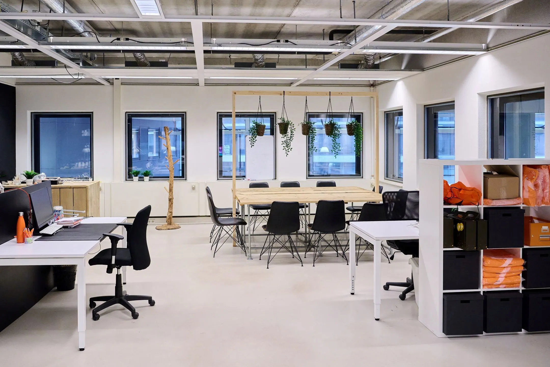 Moderne kantoorruimte aan de Johan Rözingalaan 400 met werkplekken, vergadertafel, hangplanten en opbergkasten.