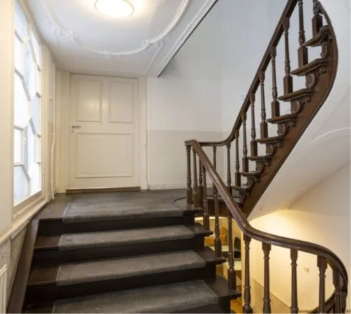 Historisch trappenhuis met houten leuning en gestoffeerde treden in een kantoorpand aan de Keizersgracht 467.