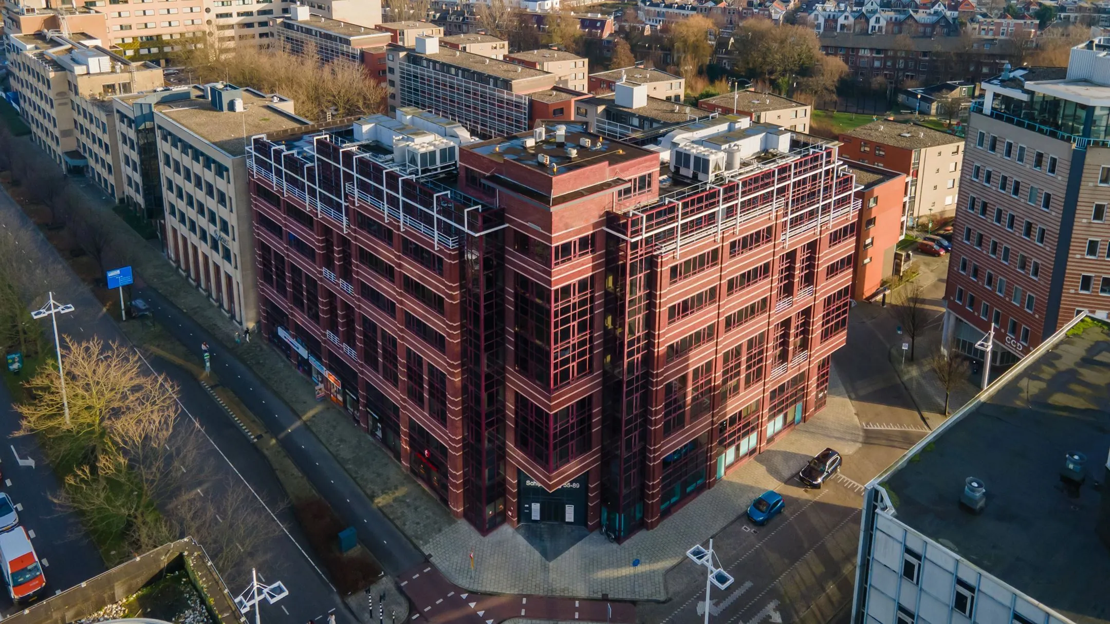 Luchtfoto van het kantoorgebouw aan de Schipholweg 55 in Leiden met omliggende bebouwing.