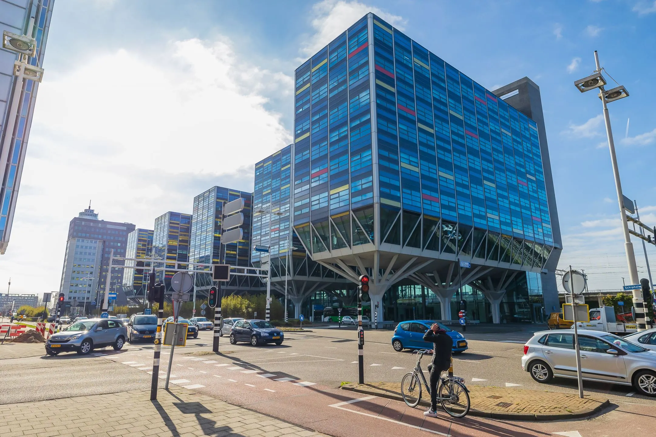 Moderne kantoorgebouwen aan de Schipholweg 55 in Leiden met opvallende gevels en druk stadsverkeer op de voorgrond.