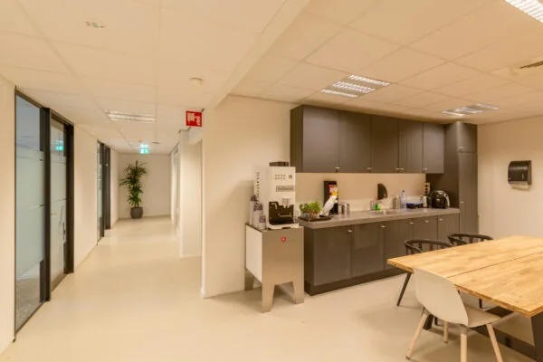 Moderne pantry met koffiemachine, keukenkasten en zithoek in kantoorruimte aan de Reactorweg 301.