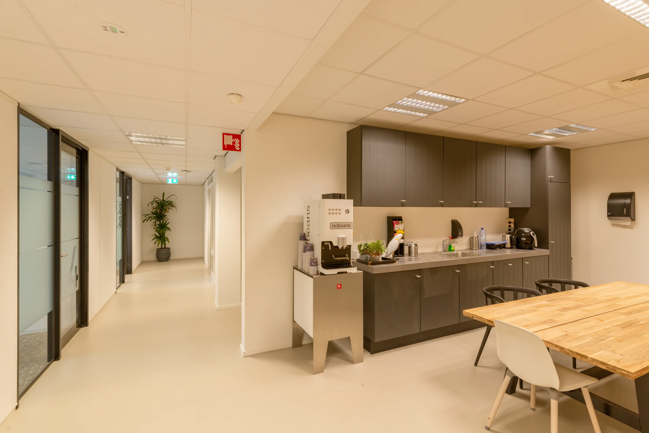Moderne pantry met koffiemachine, keukenkasten en zithoek in kantoorruimte aan de Reactorweg 301.