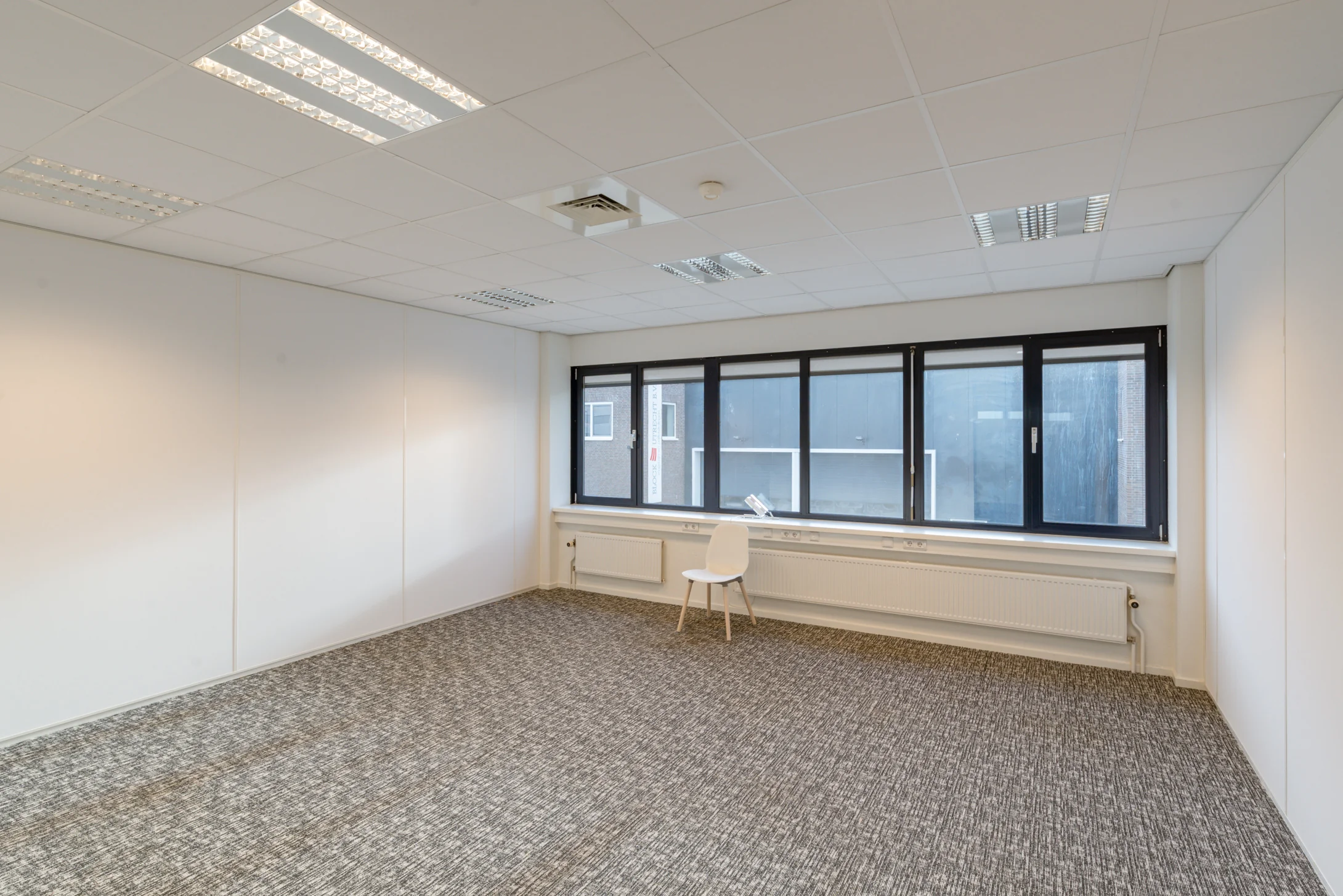 Lichte, leegstaande kantoorruimte met grijs tapijt en grote ramen aan de Reactorweg 301.