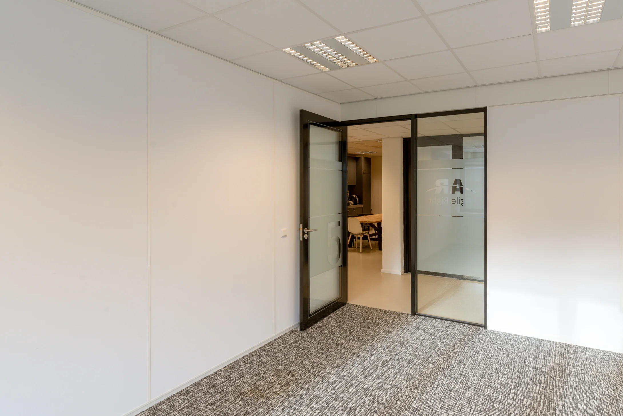 Moderne, lichte kantoorruimte aan de Reactorweg 301 met glazen deur naar een vergaderruimte.