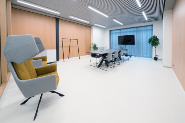 Moderne vergaderruimte aan de Wardropstraat 5 met een lange tafel, designstoelen, hoge fauteuils en een flatscreen.