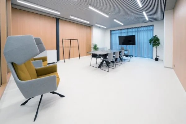 Moderne vergaderruimte aan de Wardropstraat 5 met een lange tafel, designstoelen, hoge fauteuils en een flatscreen.