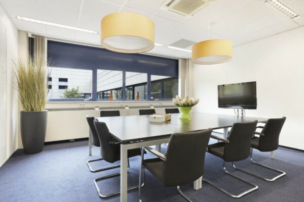 Moderne vergaderruimte in kantoorpand aan de Markerkant in Almere, met grote tafel, zwarte stoelen, flatscreen en raampartij.