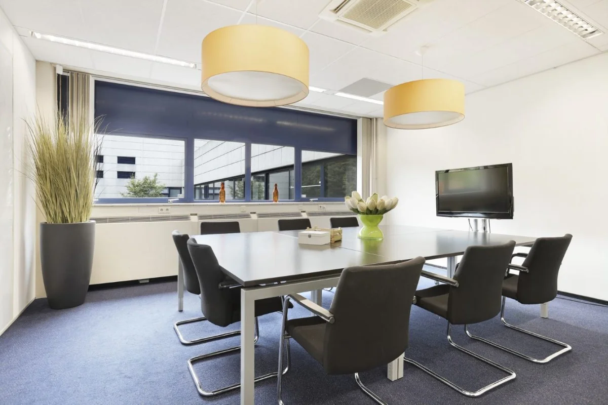 Moderne vergaderruimte in kantoorpand aan de Markerkant in Almere, met grote tafel, zwarte stoelen, flatscreen en raampartij.