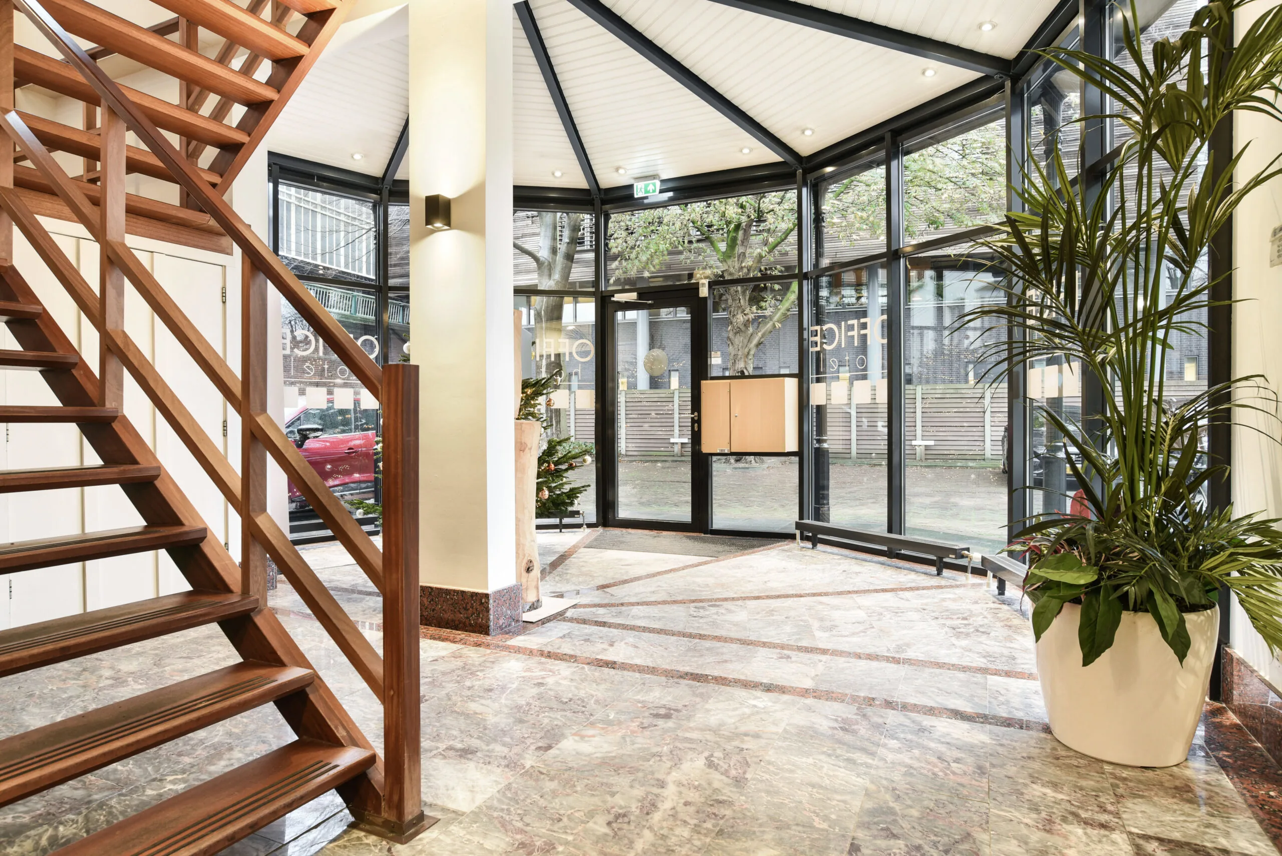 Entreehal van kantoorpand Kennemerplein 20 in Haarlem met marmeren vloer, houten trap en grote glazen gevel.