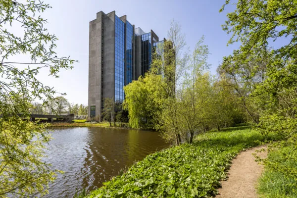 Kantoorgebouw Kronenburg van Paul Starink aan het water, omringd door groen en een wandelpad.