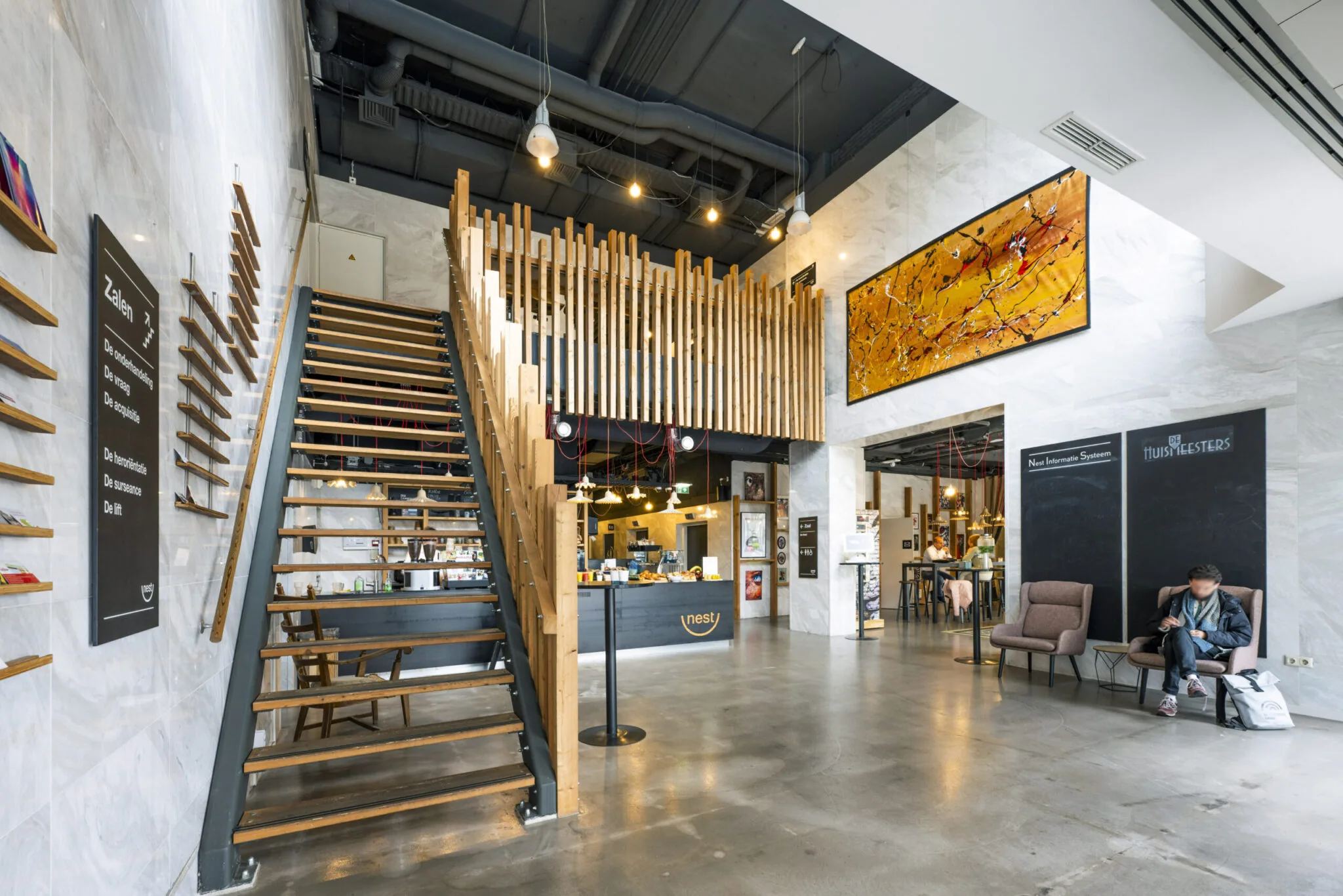 Moderne, open lobby van Kronenburg 010 met houten trap, kunst aan de muur en zitgedeelte met wachtruimte.