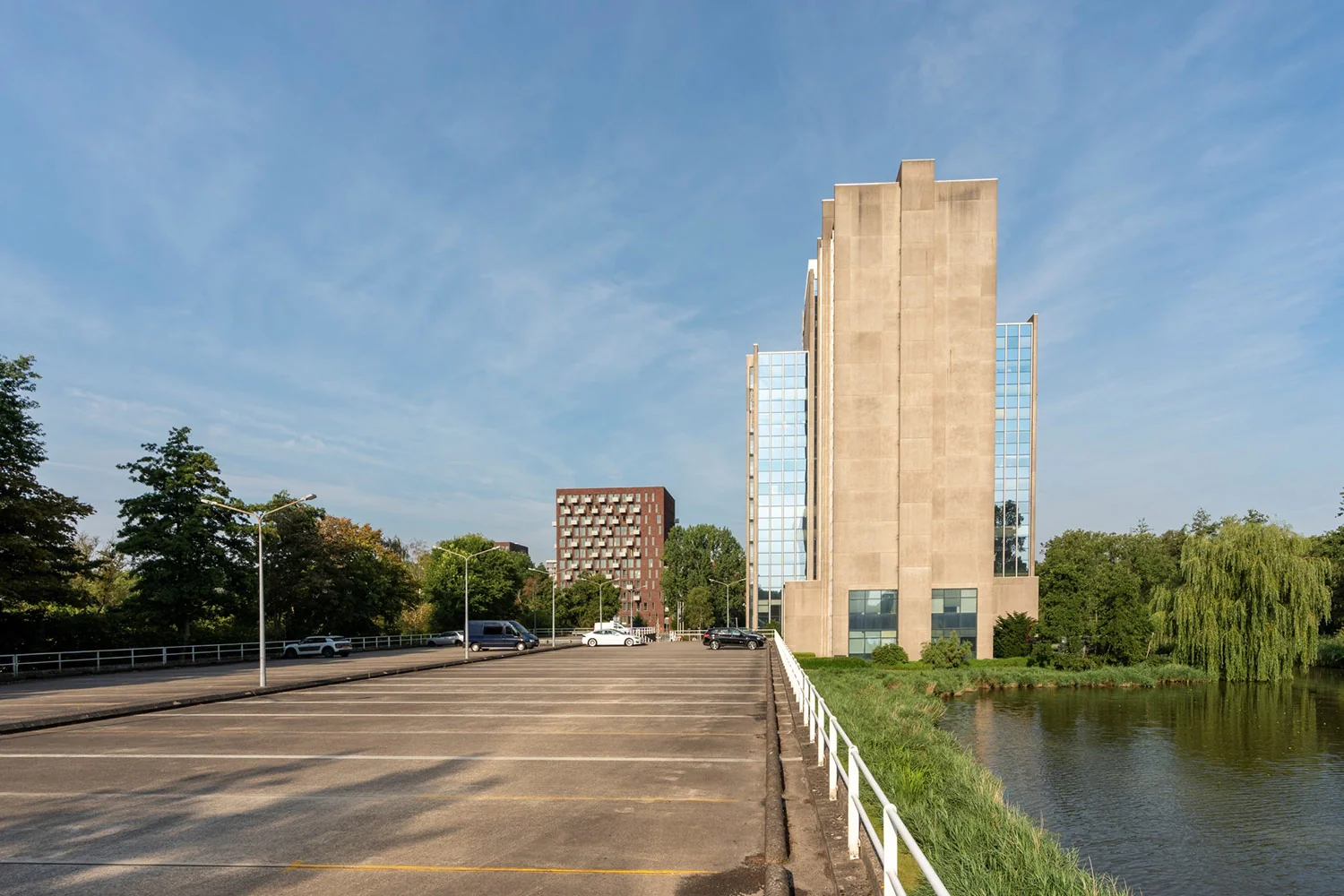 Kantoorgebouw aan de Laan van Kronenburg met parkeerplaats en waterpartij op de voorgrond.