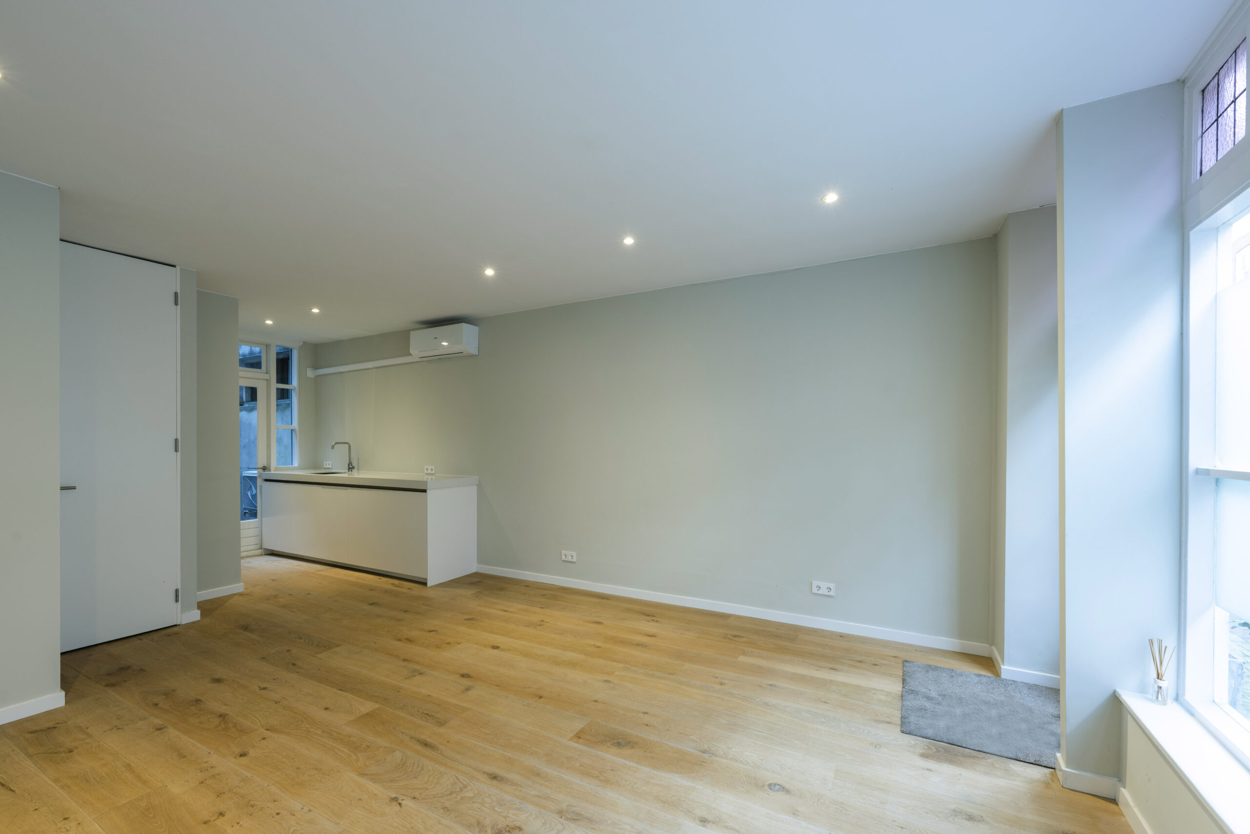 Moderne, lichte woonkamer met houten vloer en open keuken in een woning aan de Leliestraat, ontworpen door Paul Starink.