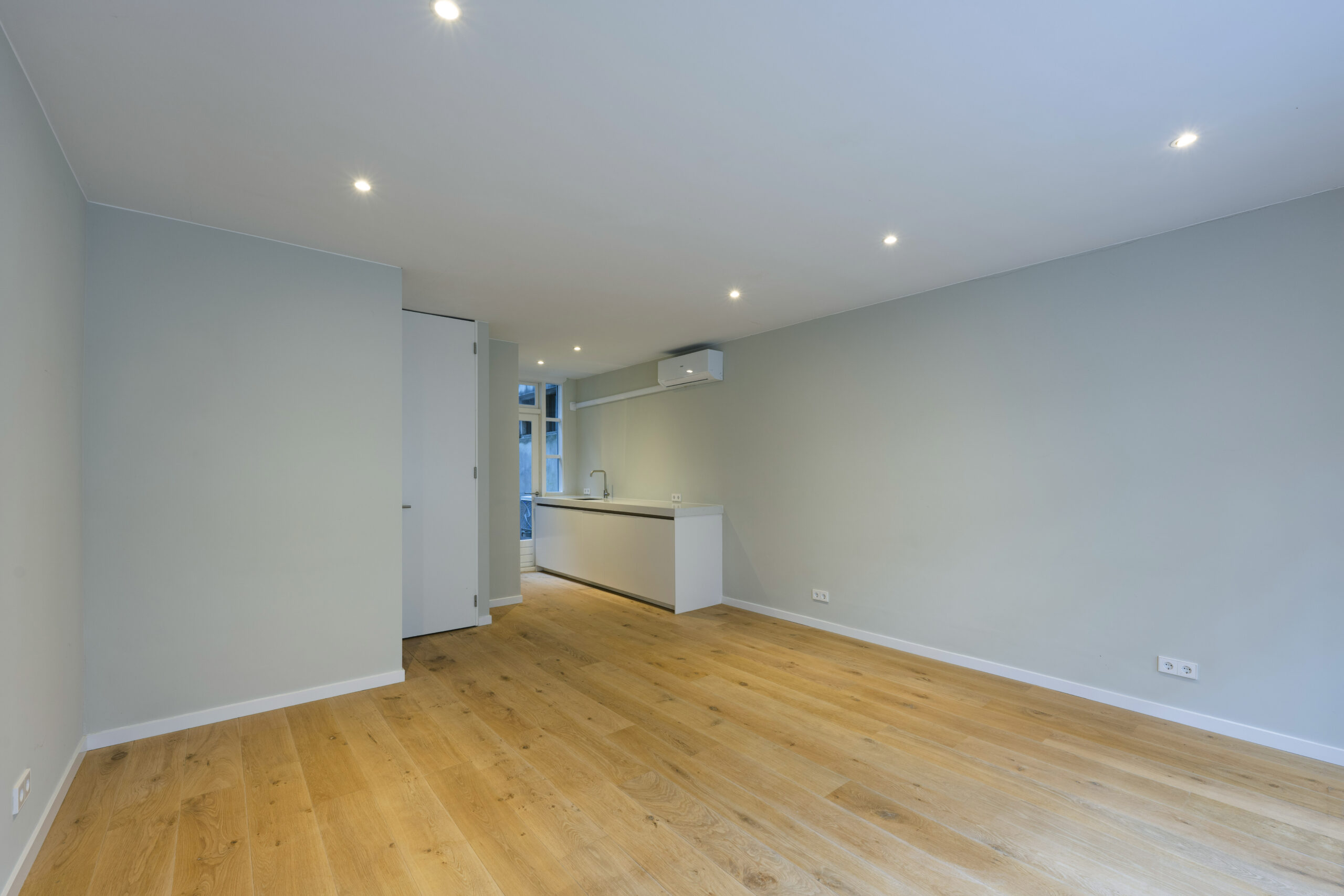 Modern ingerichte, lege woonkamer met houten vloer en open keuken aan de Leliestraat.