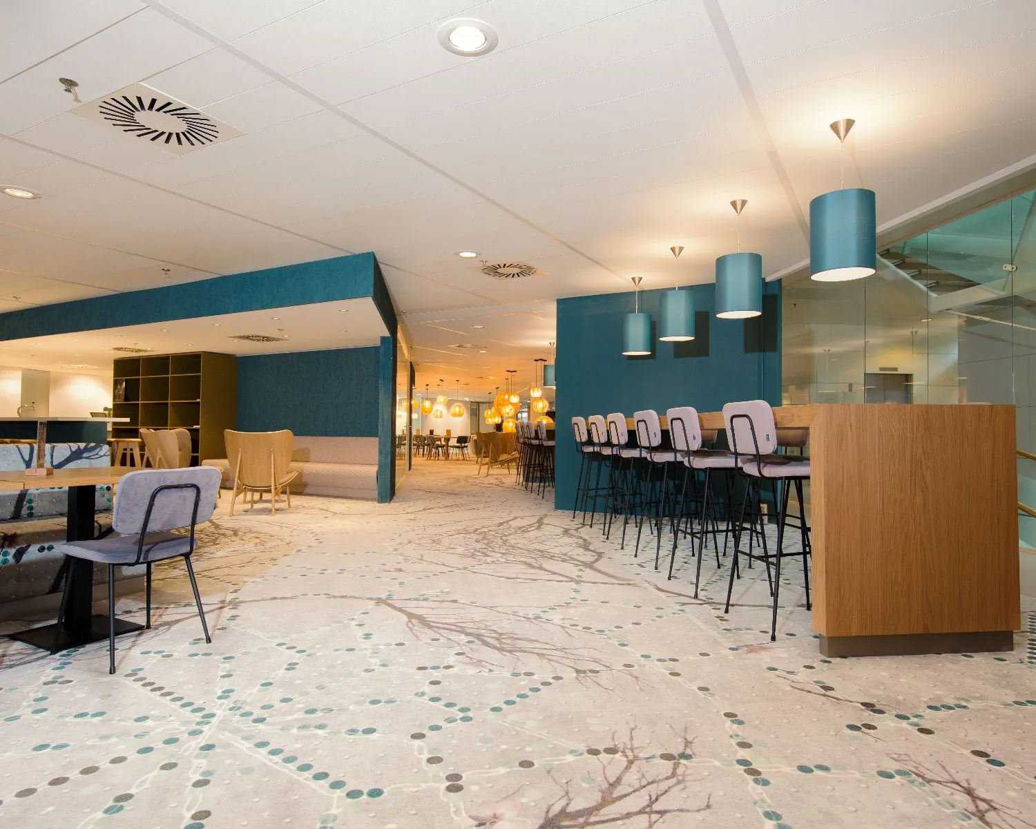 Modern ingericht café met hoge zitplaatsen, sfeerverlichting en een open, lichte indeling.