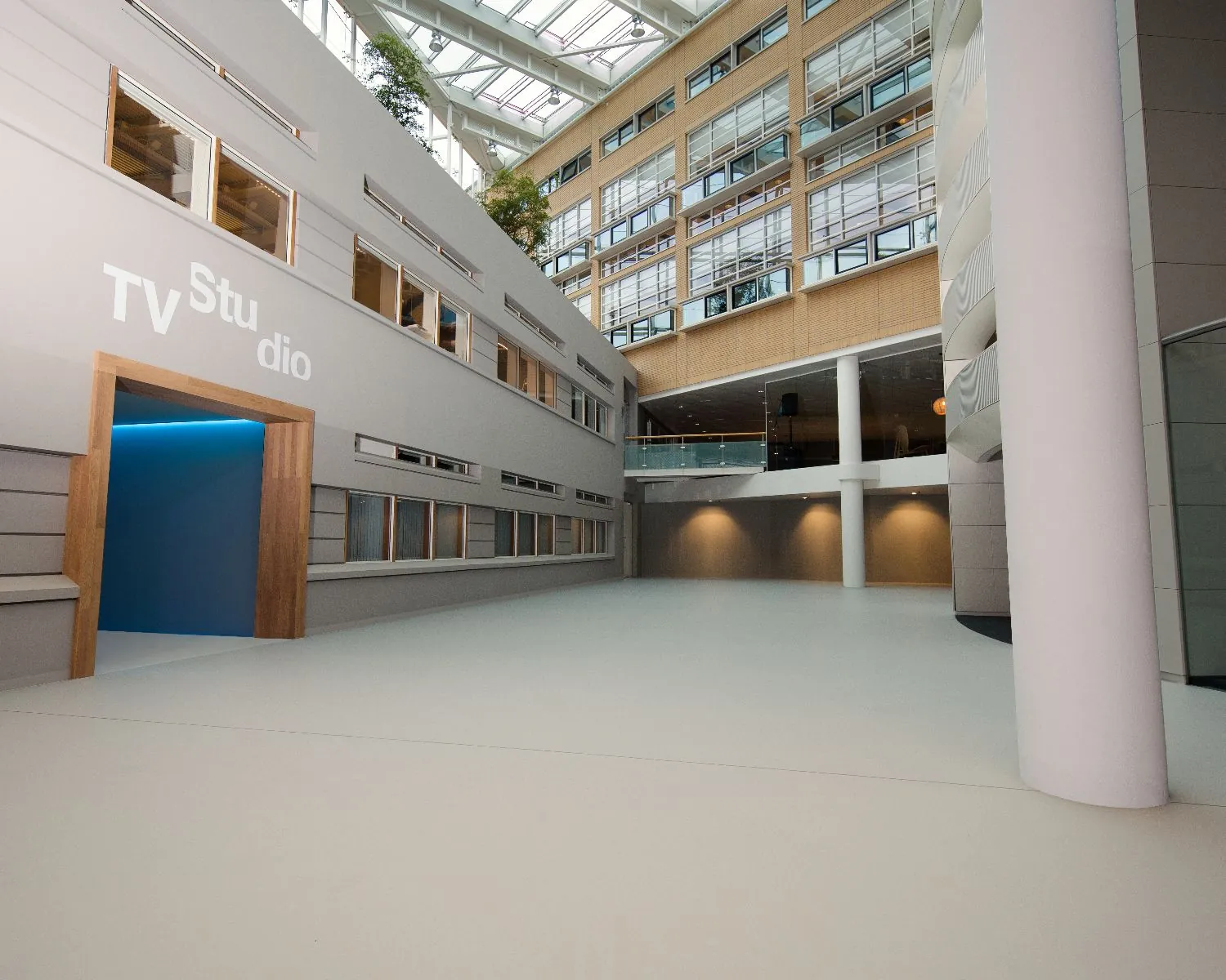 Ruime, moderne hal van een kantoorgebouw met een ingang naar een TV-studio.