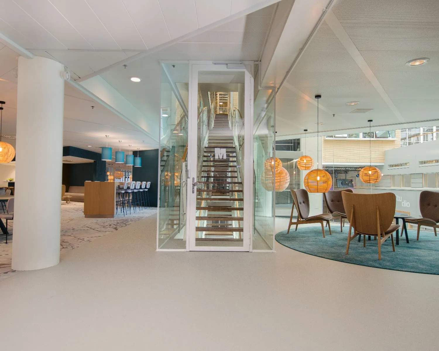 Modern kantoorinterieur met een kleine glazen trap in het midden en zitgedeeltes aan beide zijden.