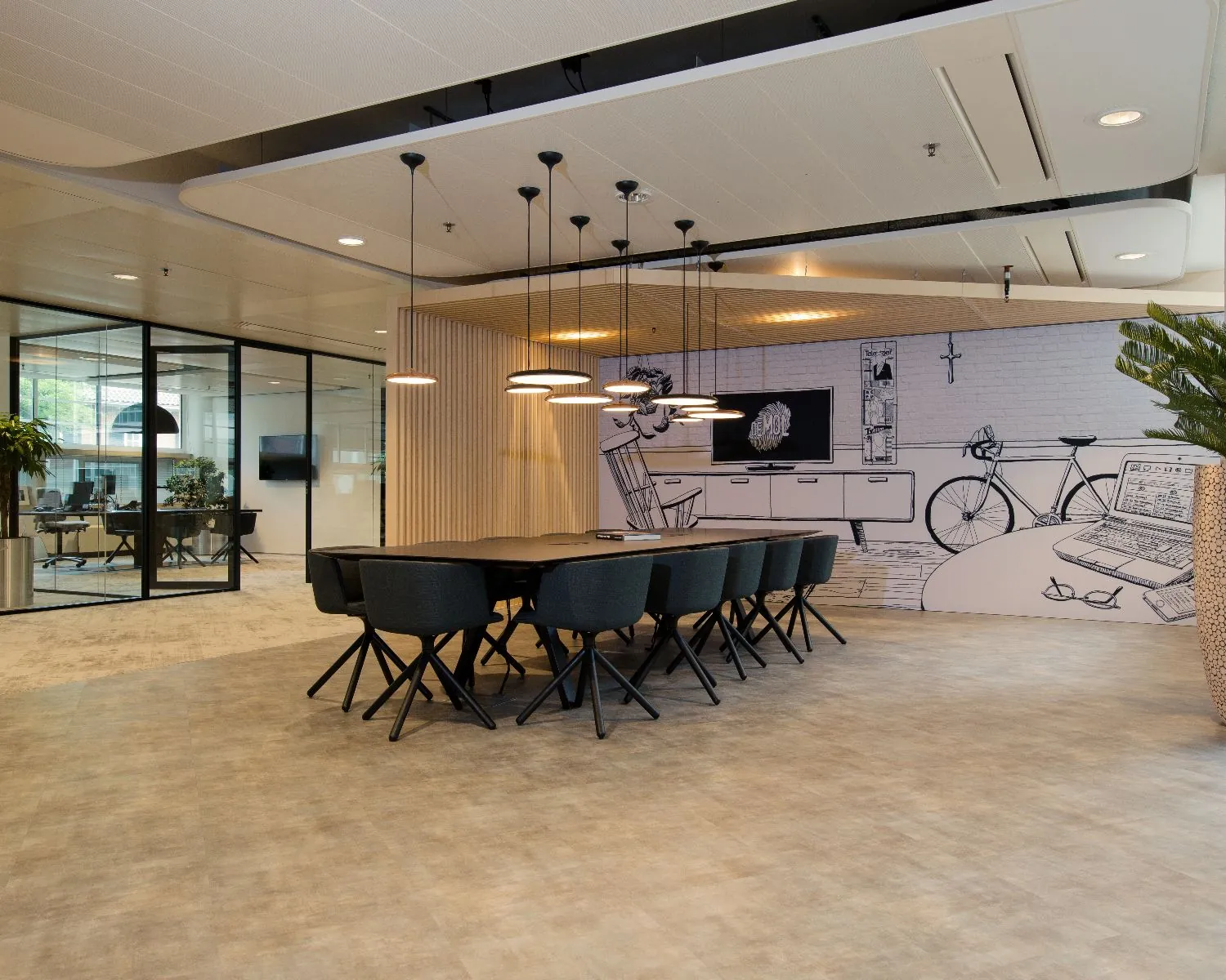 Moderne vergaderruimte met lange tafel, zwarte stoelen en een muur met creatieve illustraties.