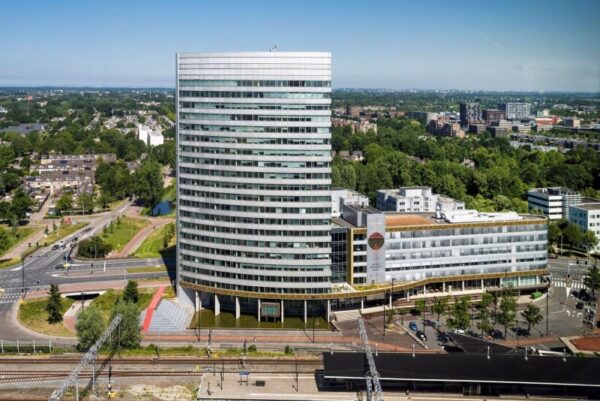 Een hoog, modern kantoorgebouw genaamd Mercuriusplein, omgeven door groene bomen en stedelijke infrastructuur.