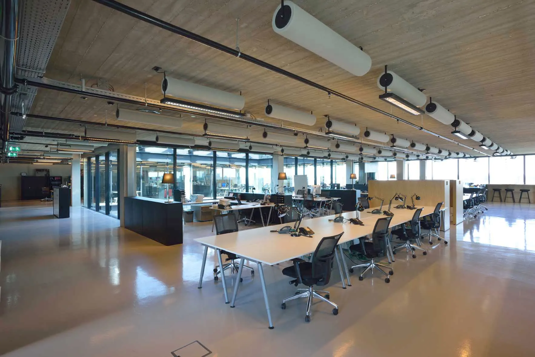 Moderne, open kantoorruimte in Moermanskade 109 met flexwerkplekken, glazen wanden en industriële plafonddetails.