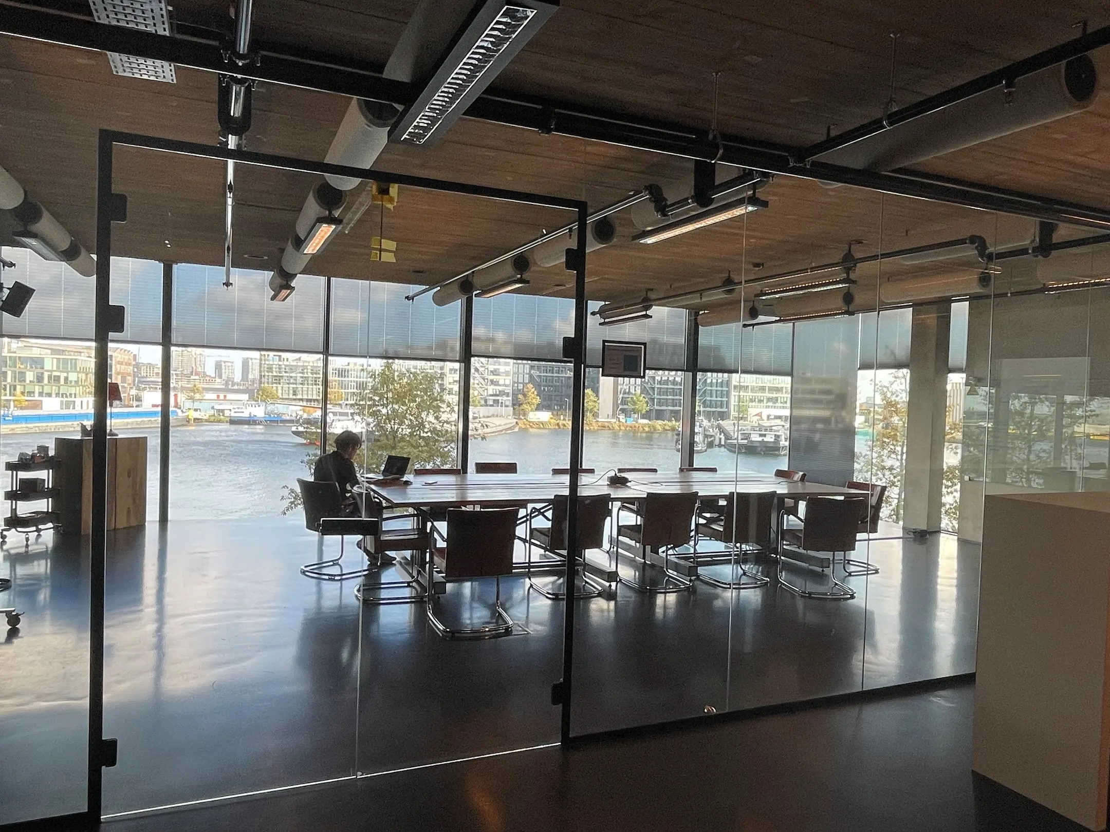 Vergaderruimte aan de Moermanskkade met glazen wanden en uitzicht op het water.