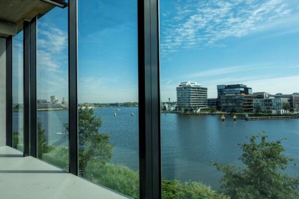 Uitzicht vanuit een modern kantoorgebouw aan de Moermanskkade op het water en omliggende kantoren aan de overzijde.