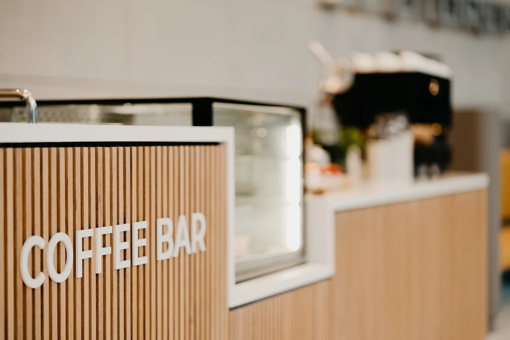Moderne koffiebalie met houten panelen en het opschrift "Coffee Bar" op de voorkant.