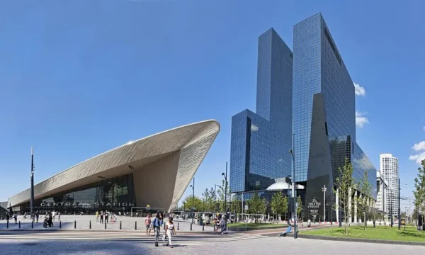 Modern view of Rotterdam Centraal Station with high-rise buildings in the background on a clear day.