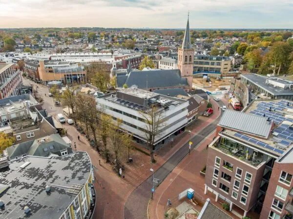 Luchtfoto van het gebouw aan de ’s-Gravelandseweg 9 in Hilversum, met de omliggende straat en kerk op de achtergrond.