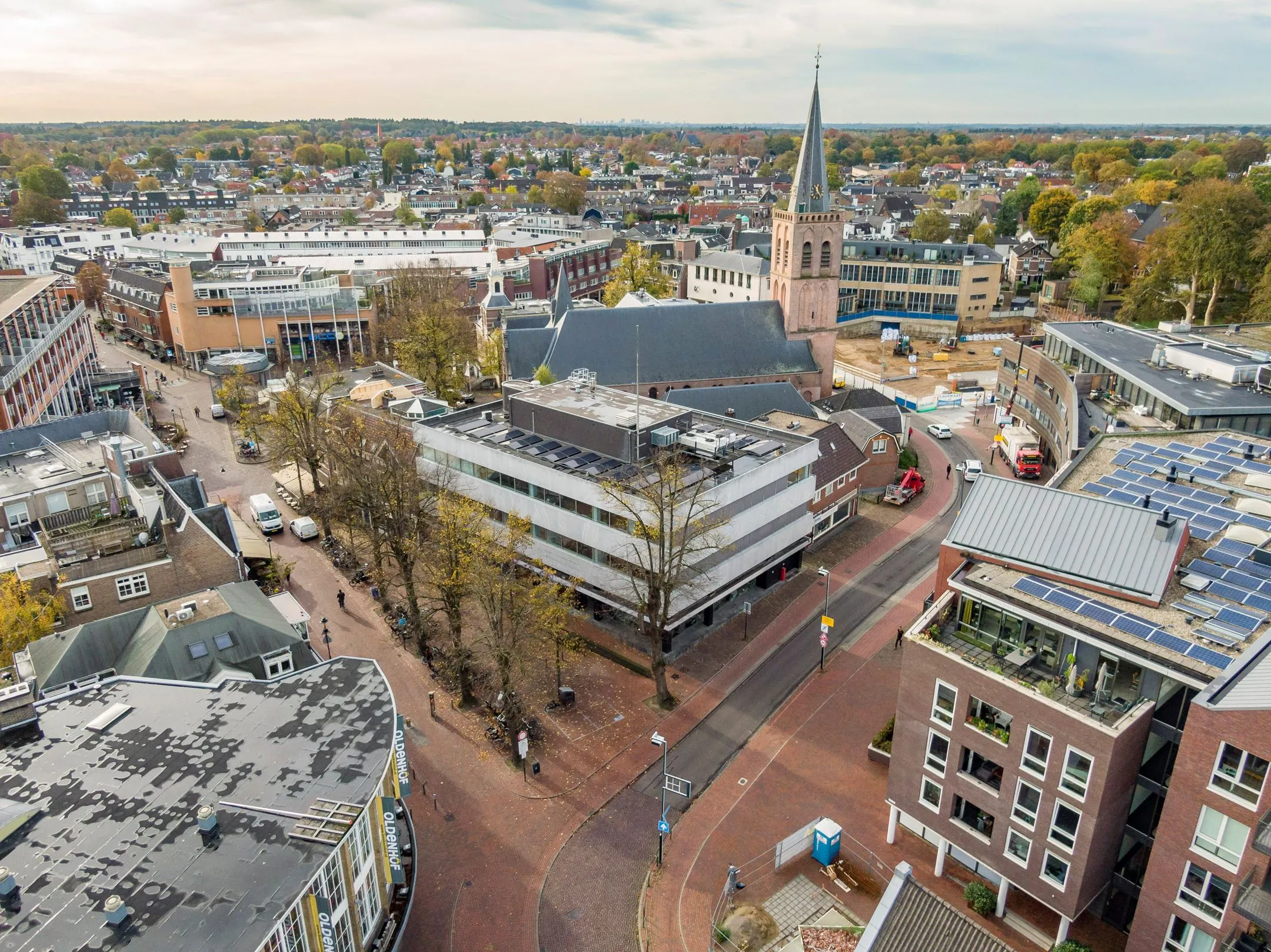 Luchtfoto van het gebouw aan de ’s-Gravelandseweg 9 in Hilversum, met de omliggende straat en kerk op de achtergrond.