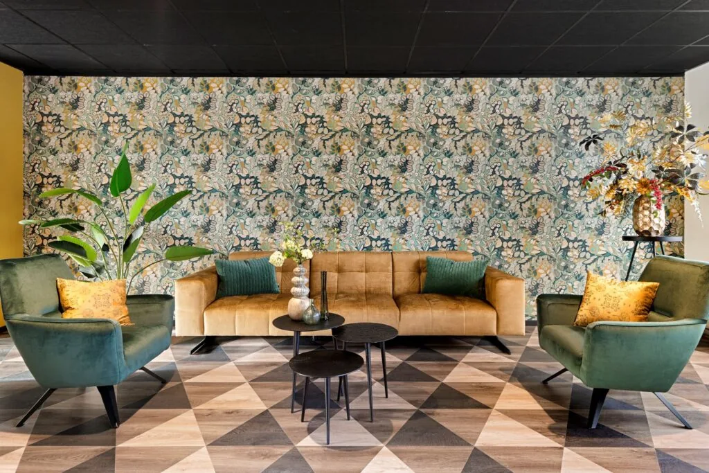 Stijlvolle zithoek aan de ‘s-Gravelandseweg 9 met fluwelen meubels, bloemenbehang en geometrische vloer.