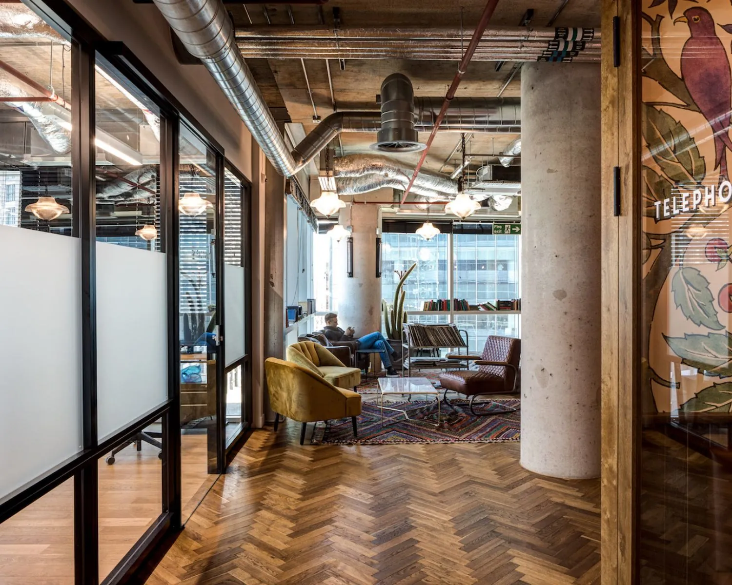 Modern ingerichte loungeruimte in een kantoor aan de Spuistraat 111 met industriële details en houten visgraatvloer.