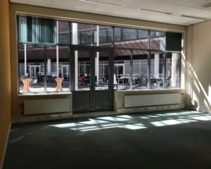 Lichte kantoorruimte met grote ramen en uitzicht op een binnentuin aan de Burgemeester van Karnebeeklaan 14 in Den Haag.