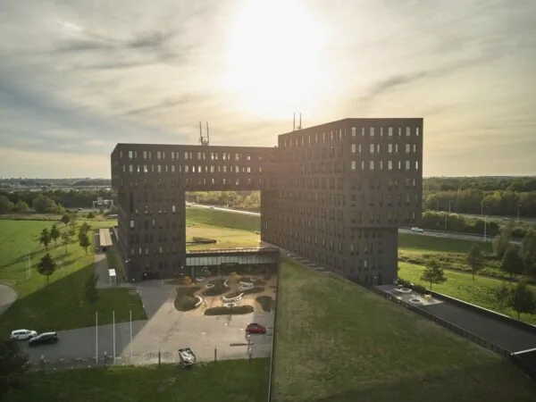 Moderne kantoorlocatie aan de Van Deventerlaan 31-51 met opvallend U-vormig gebouw en groene omgeving bij ondergaande zon.