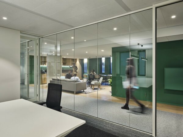 Moderne kantoorruimte aan de Van Deventerlaan 31-51 met glazen wanden, loungegedeelte en mensen in gesprek.