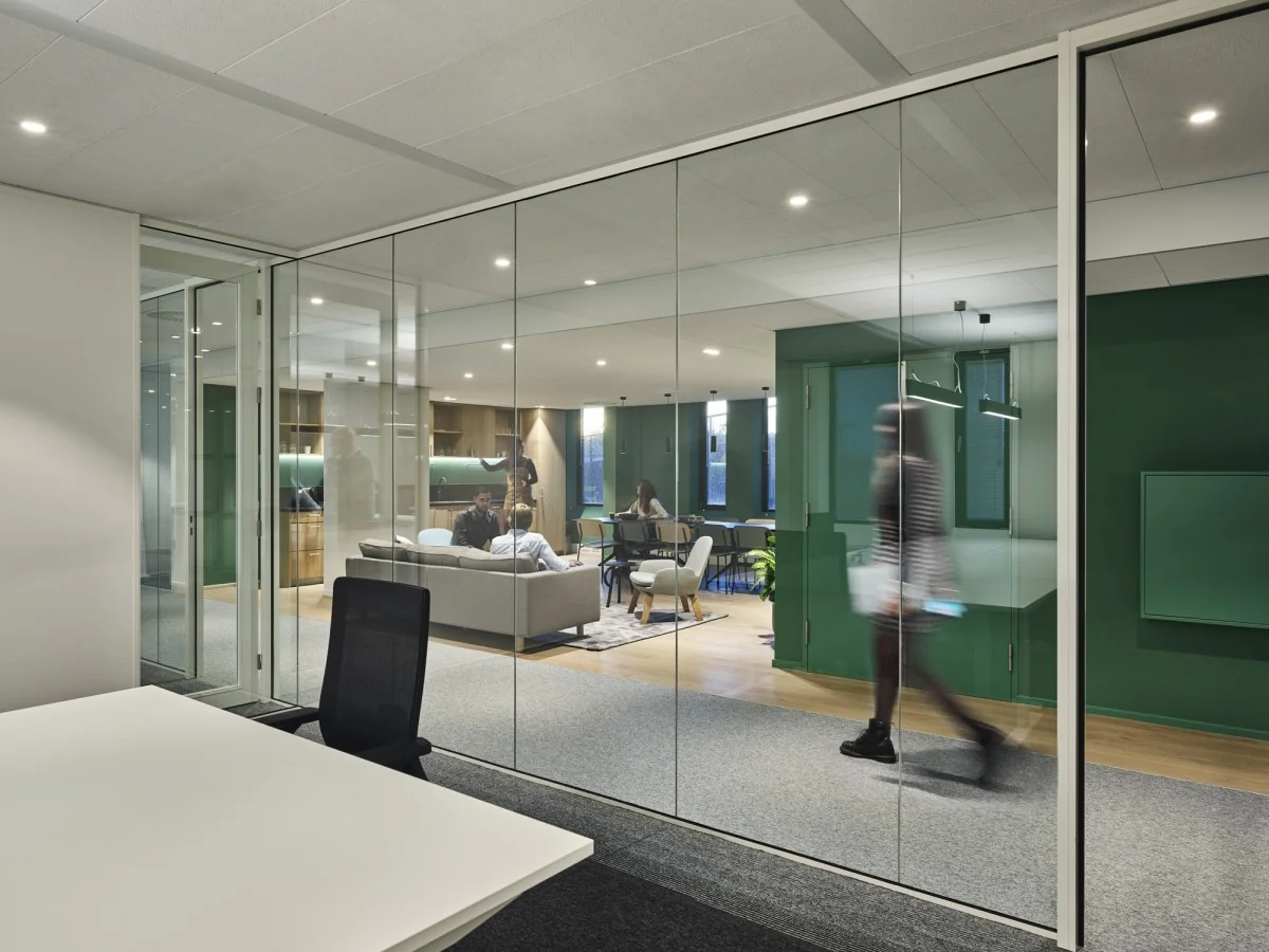 Moderne kantoorruimte aan de Van Deventerlaan 31-51 met glazen wanden, loungegedeelte en mensen in gesprek.