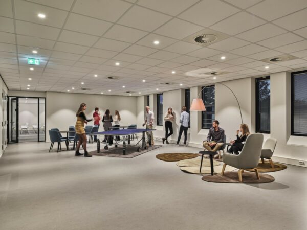 Moderne ontspanningsruimte in kantoorpand Van Deventerlaan 31-51 met mensen die tafeltennissen en loungen.