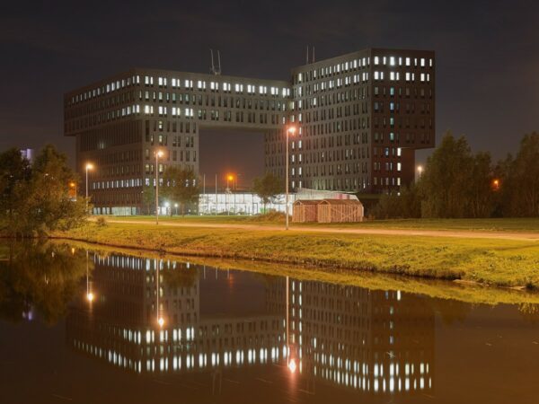 Kantoorgebouw aan de Van Deventerlaan 31-51 te Utrecht, 's avonds verlicht en weerspiegeld in het water op de voorgrond.