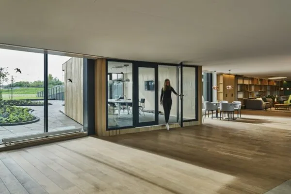 Ruim en modern interieur aan de Van Deventerlaan 31-51 met glazen vergaderruimte, zithoek en uitzicht op een groene patio.