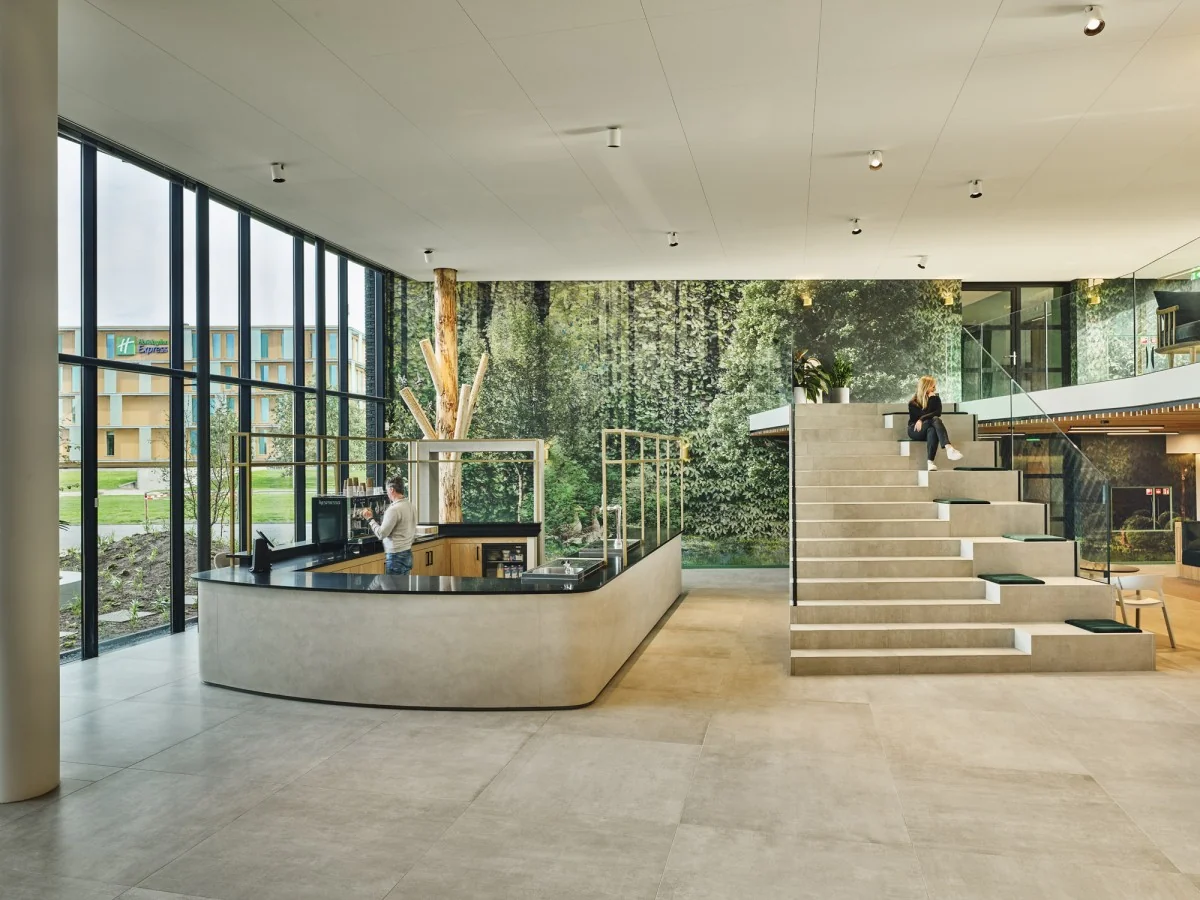 Moderne en lichte lobby van Van Deventerlaan 31-51 met een zittribune, werkplek en uitzicht op een Holiday Inn Express gebouw.